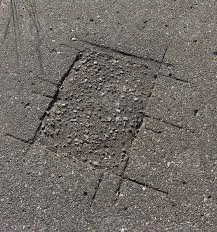 Close-up of a deep crack or permanent gouge in a driveway caused by a heavy roll-off dumpster without wood protection.